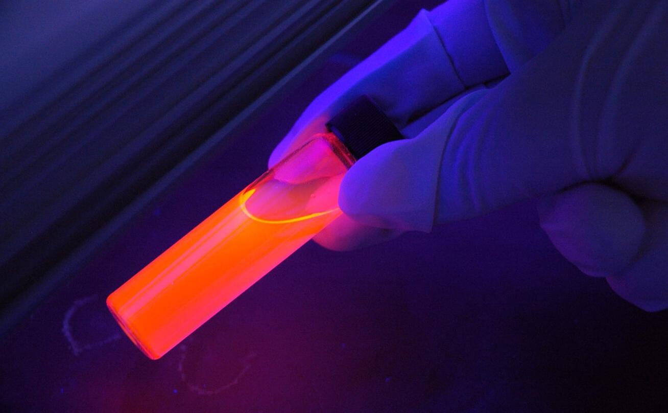Gloved hand holding glowing vial